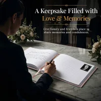 Person writing a message in a personalized funeral guestbook with rose gold accents, placed on a memorial table with flowers, creating a heartfelt keepsake filled with love and memories.