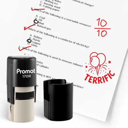 Black self inking teacher stamp and removable cap displayed beside a graded science worksheet marked with red check marks and a “10/10” score. A red balloon stamp on the page says “TERRIFIC,” showing how the classroom stamp can be used to reward student a