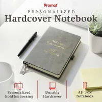 Gray hardcover notebook with gold embossed text on a desk, a personalized leather journal featuring durable A5 design and custom engraving.