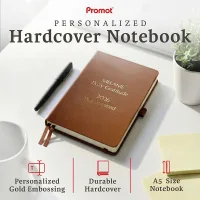 Brown personalized leather journal with custom gold embossed text, displayed on a desk to highlight its durable hardcover and A5 size.
