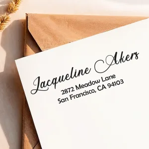A clean return address from a medium self-inking address stamp shown on a white envelope with a kraft envelope underneath.